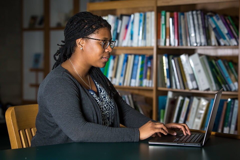 Image of a woman searching on a laptop in the library